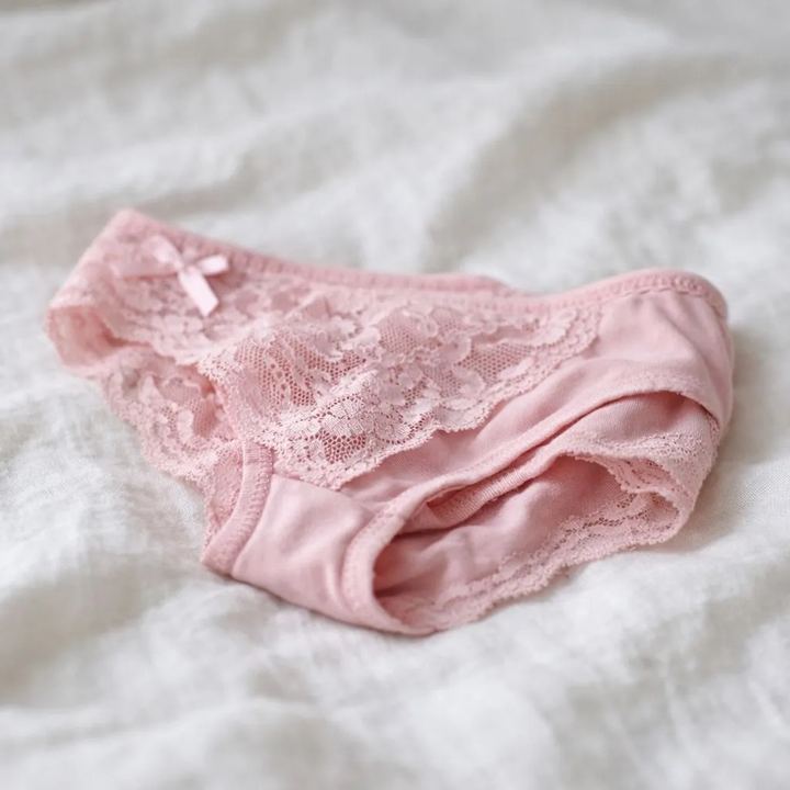 Worn pink lace panties lying on a bed